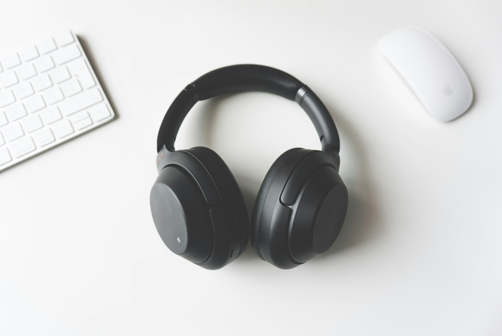Headphones on a white desk next to a keyboard
